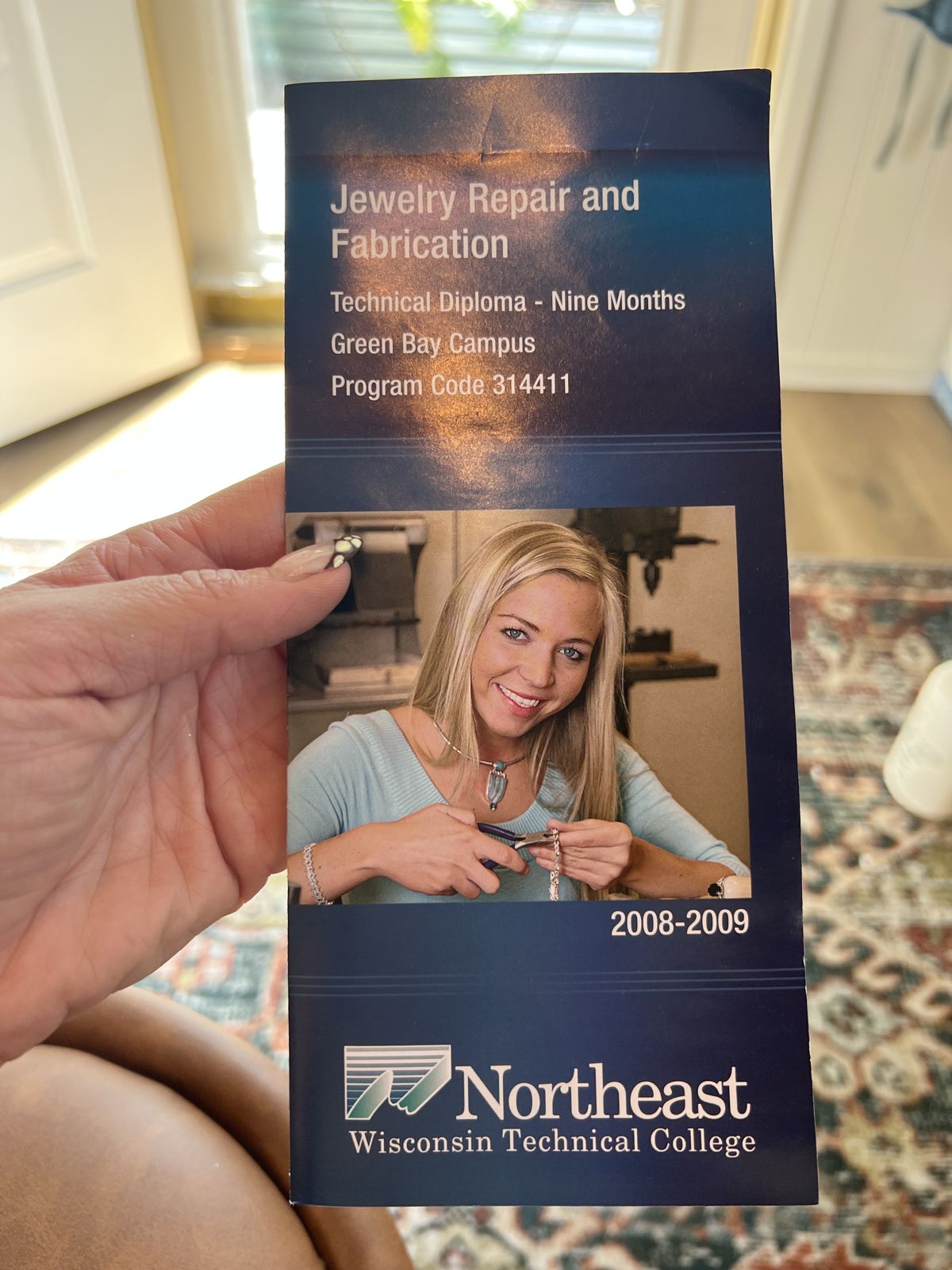 Alex holding the jewelry school brochure with her own photo on the cover, 2008-2009