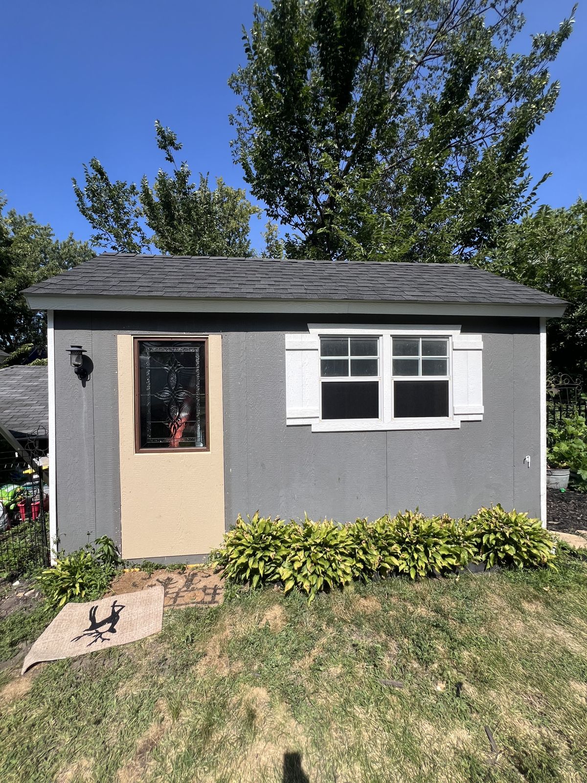 The little shed behind the house before renovation, under a blue sky